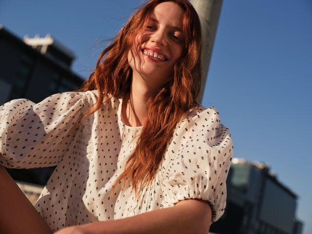 One woman wearing a navy and white striped co ord with a shirt and matching wide leg trousers, holding a beige handbag. Another woman wearing a beige pinstripe co ord with a short sleeved top and wide leg trousers.