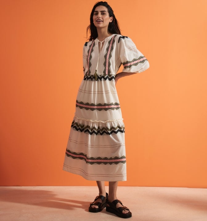 Women wearing an aztec print midi dress with long sleeves and tie neck detail.